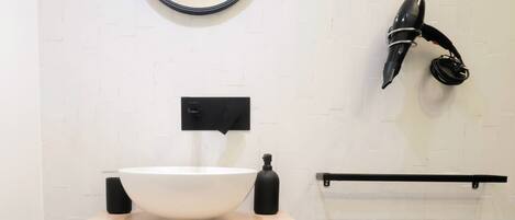 A modern bathroom with a white sink, black faucet, and a round mirror.