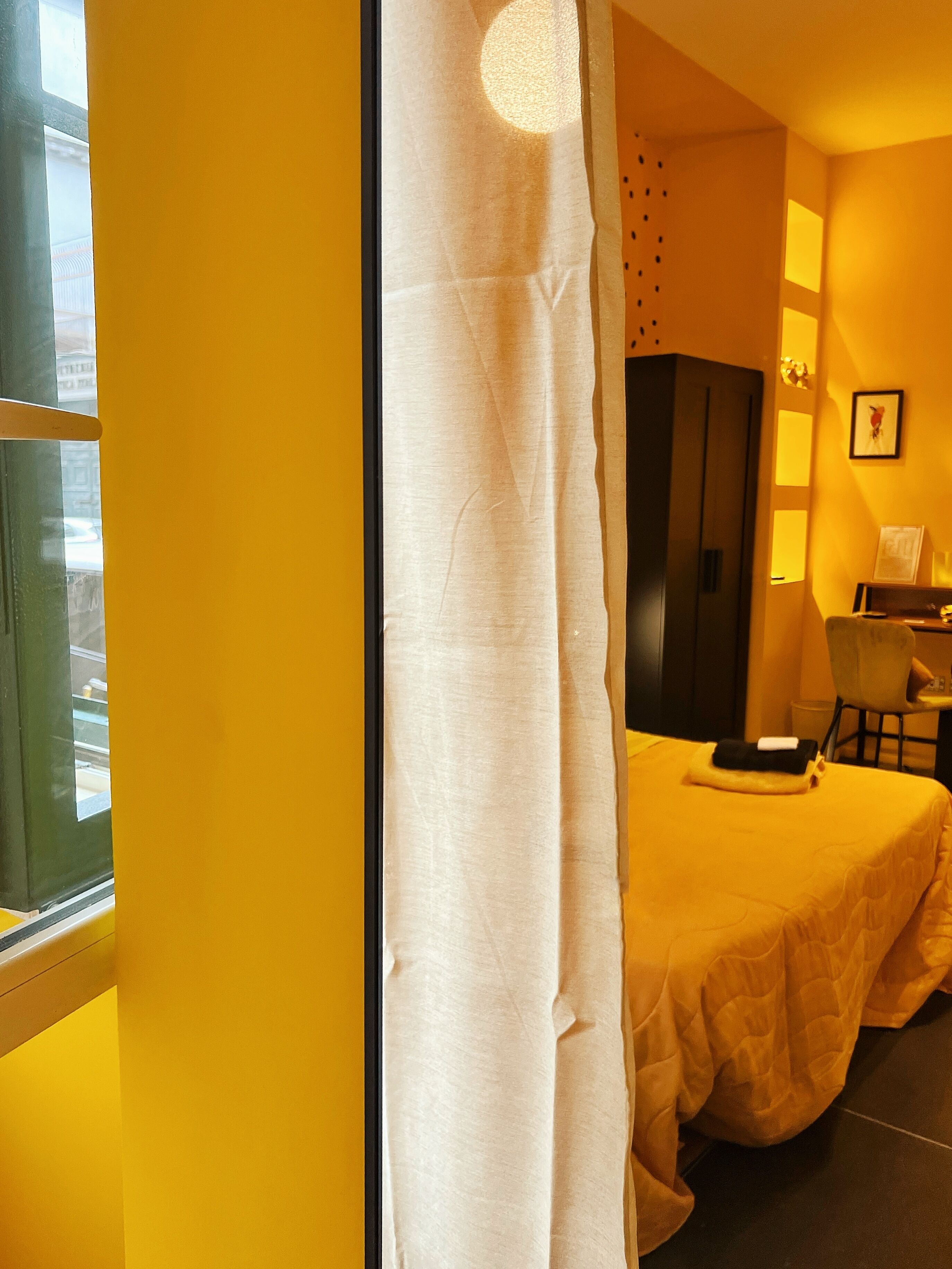Ein Hotelzimmer mit Bett, Stuhl, Kleiderschrank und einem fensterbepflanzten Fenster.
