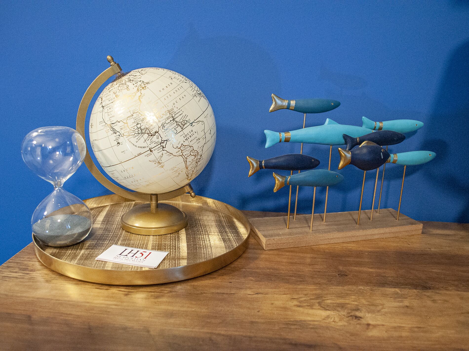 Un globe terrestre posé sur un socle en bois, avec une étiquette portant l’inscription « LHS1 » et un sablier.