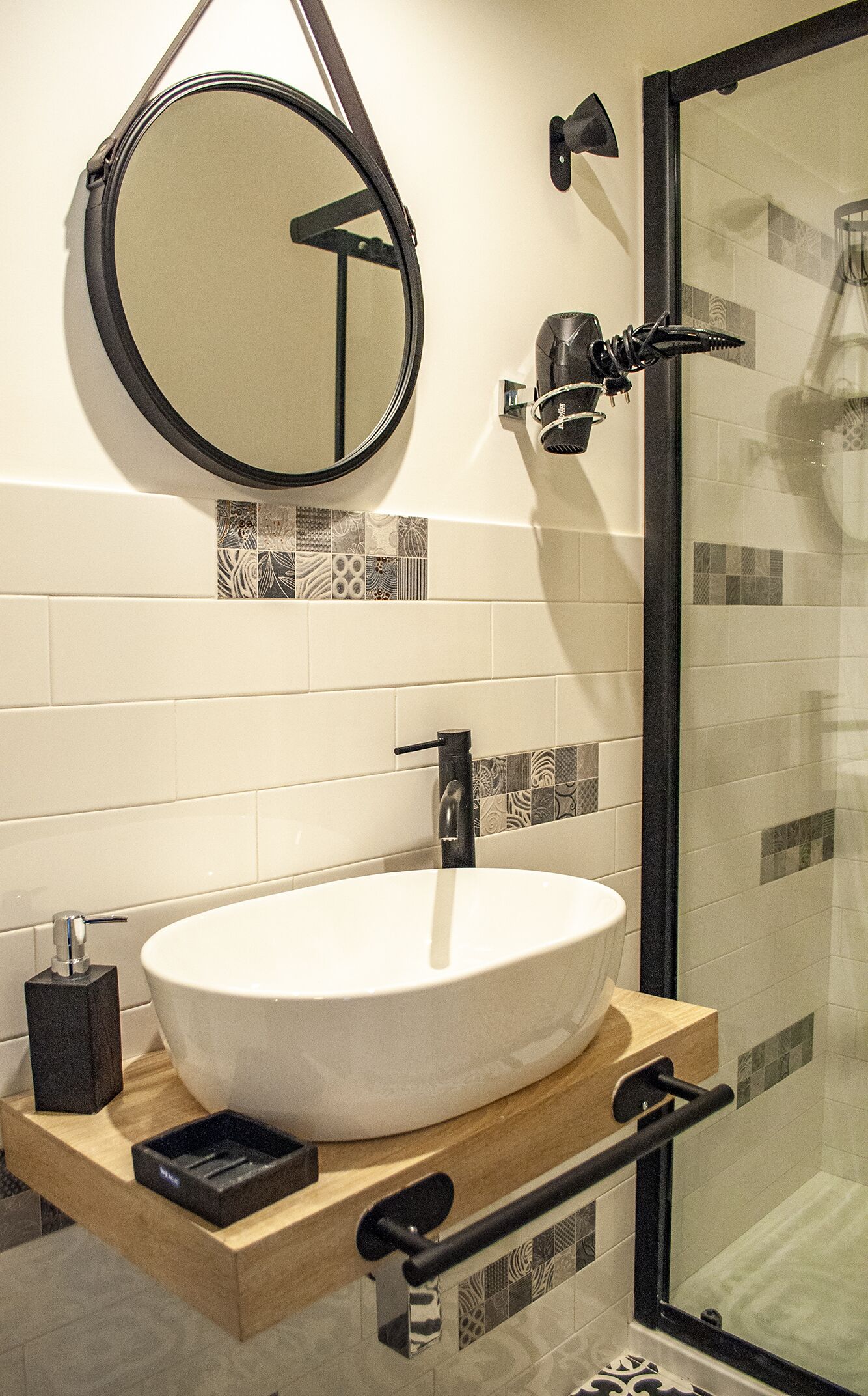 Une salle de bain avec un miroir rond, un lavabo blanc et un espace douche.