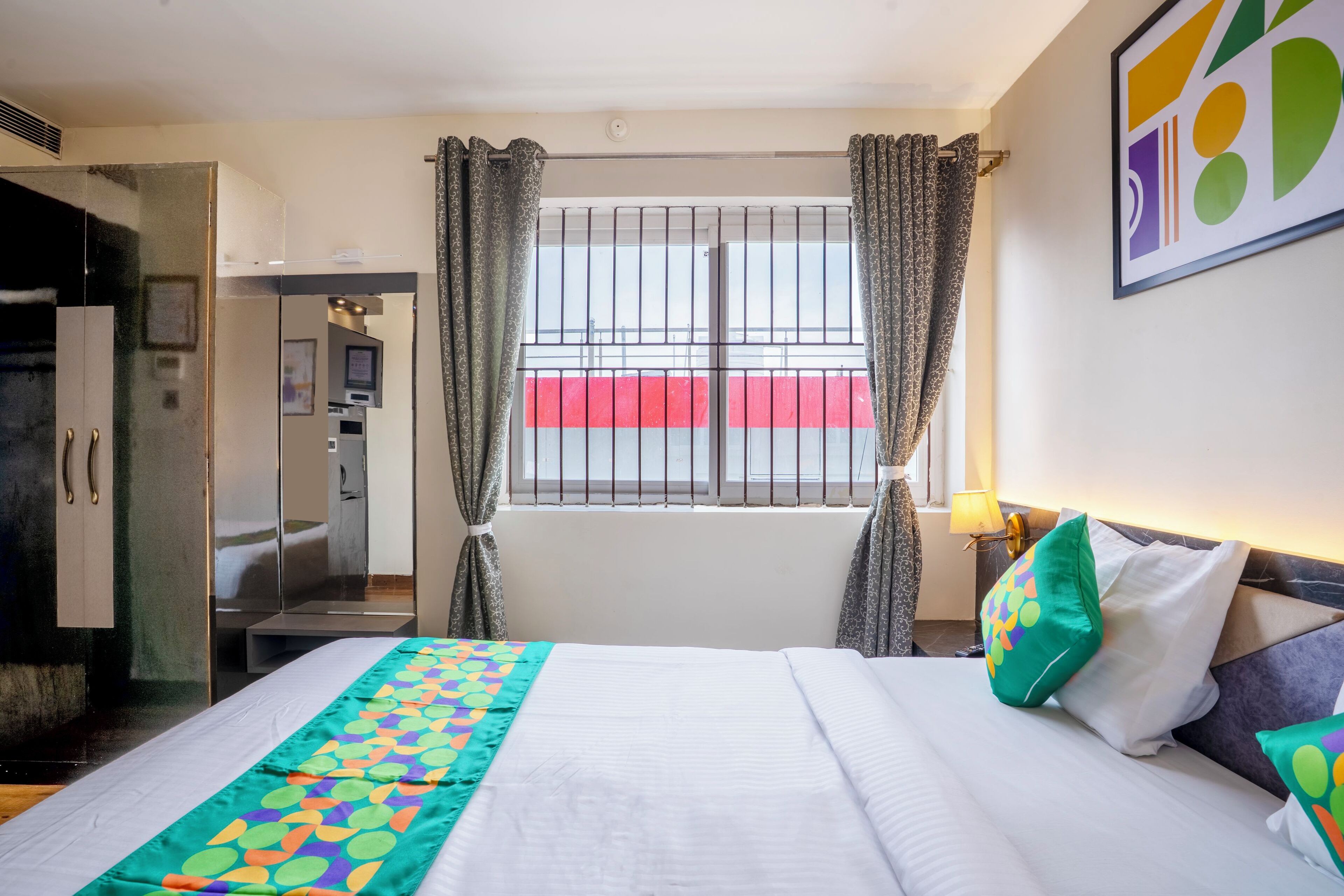 A hotel room with a bed, a wardrobe, a bathroom, and a window with curtains.