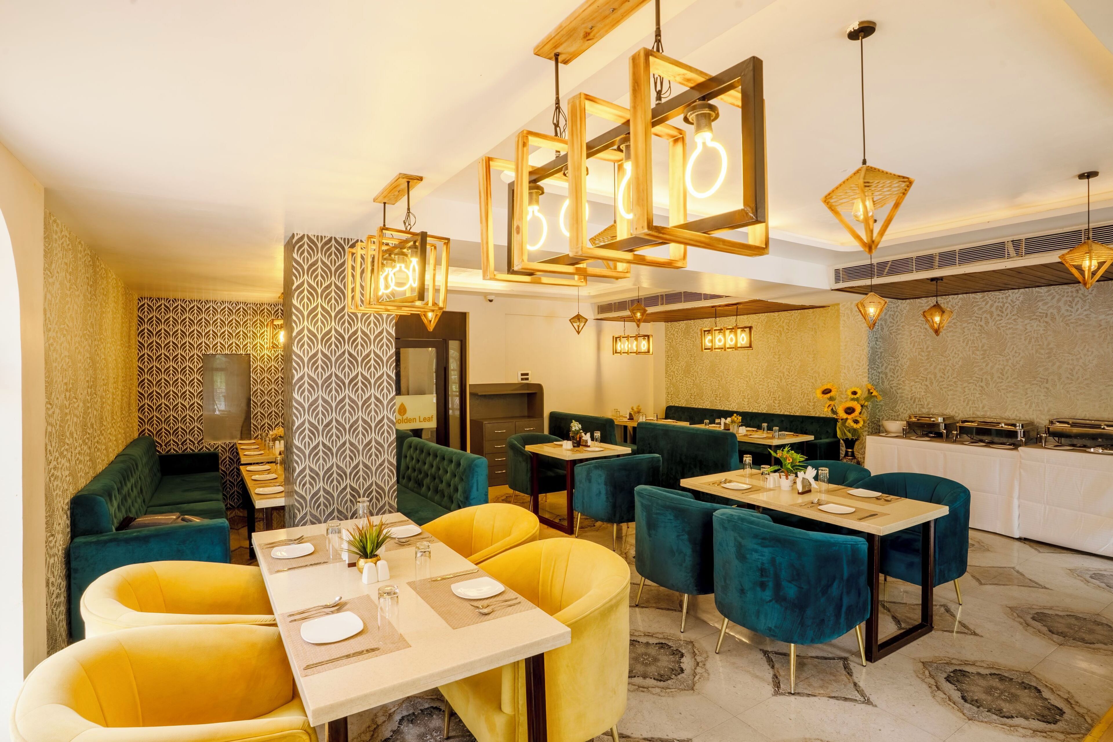 A dining area with tables and chairs, patterned wallpaper, and pendant lighting.