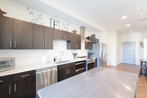 A modern kitchen with dark wood cabinets, stainless steel appliances, and a large marble countertop.