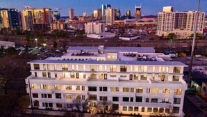 A multi-story hotel with a flat roof and uniform window design, surrounded by a cityscape at dusk. - Experience the best of Nashville from this stunning downtown condo, just 1.2 miles from Broadway’s live music, restaurants, and nightlife. Featuring a resort-style pool, and secure garage parking. (Nashville)