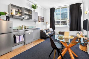 Eine moderne Küche mit Essbereich, einer Couch und einem großen Fenster mit Vorhängen.
