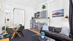 A compact living space with a kitchenette, a dining area, and a seating area with a couch. - Stay in Aucklands Iconic Queen St  Zodiak Stays (Auckland)