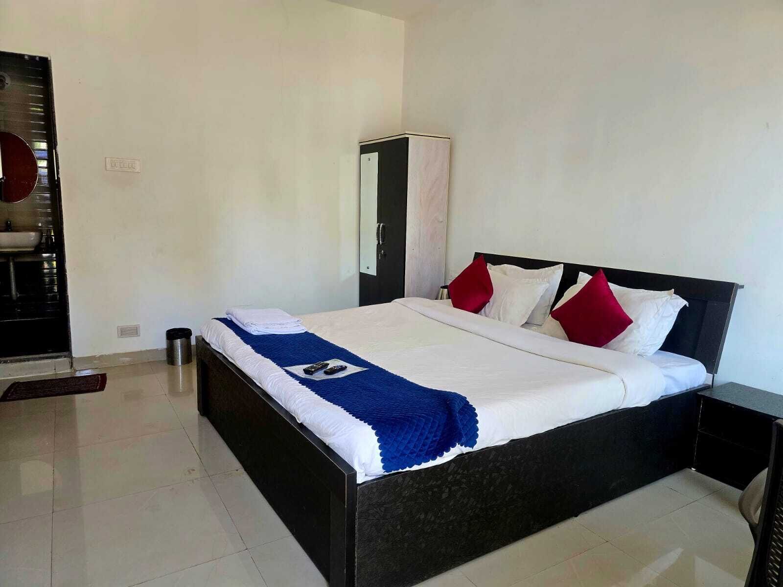 A hotel room with a bed, a small bedside table, a mirror, and a wardrobe.