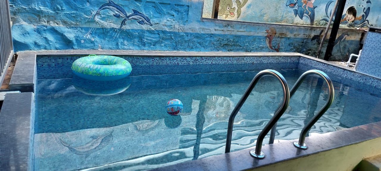 Ein Schwimmbecken mit Mosaikfliesen, einem blauen Luftreifen und einem Tauchbrett.