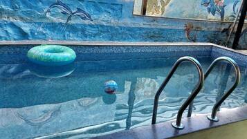 Ein Schwimmbecken mit Mosaikfliesen, einem blauen Luftreifen und einem Tauchbrett.