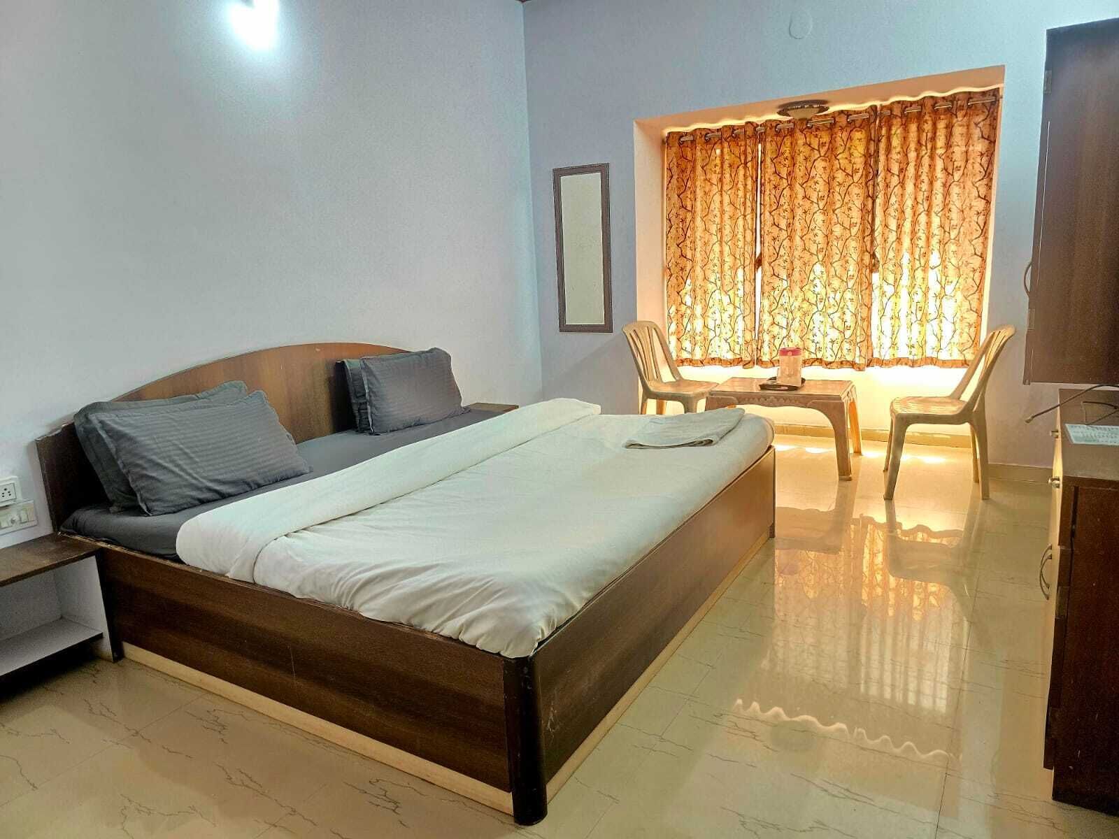 Un dormitorio con cama, escritorio, silla y ventana con cortinas.
