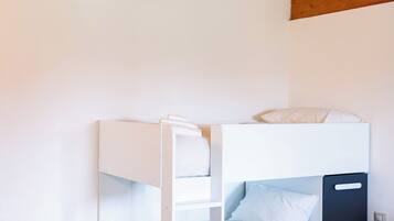 Un lit superposé avec une tête de lit blanche, une petite étagère et une table de chevet.