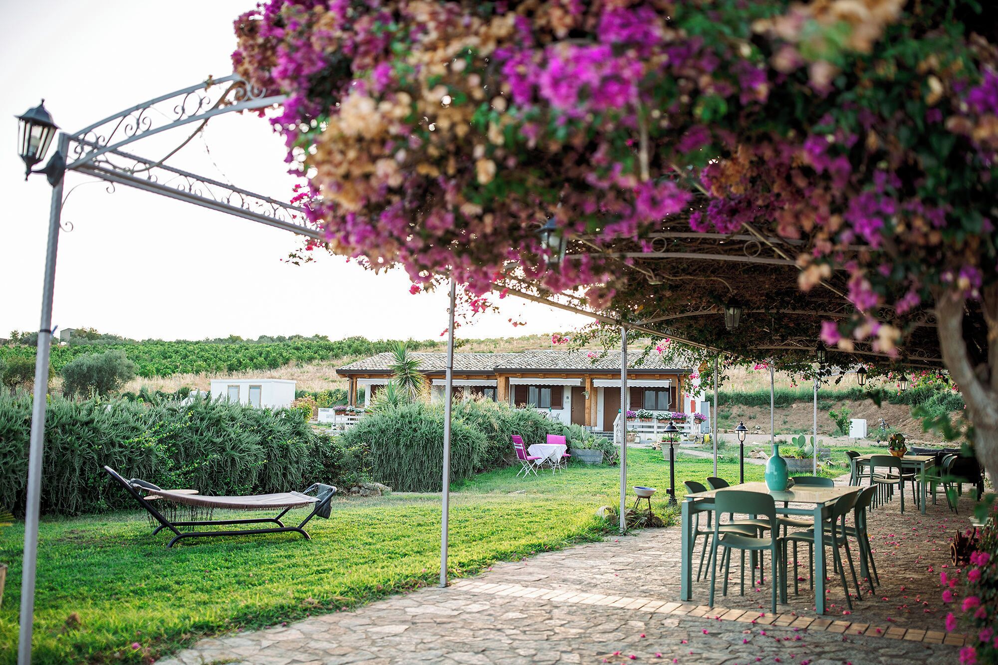Un jardin agrémenté d’une pergola, d’un espace salon extérieur et d’un bâtiment en arrière-plan.