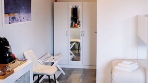 A modern room with a wooden ceiling, a white wardrobe, a white sofa, a small table, and a chair. - Agritourism. Accommodation x 4 + 1 persons with outdoor kitchen. Garden view. (Mazzarino)