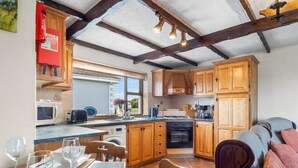 A kitchen with wooden cabinets, a microwave, a sink, and a dining area with a table set for four.