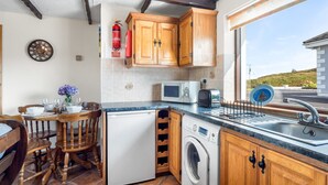 A compact kitchen with wooden cabinets, a washing machine, a microwave, and a toaster.