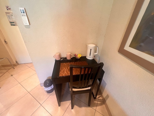 A small dining area with a table, two chairs, a kettle, and a trash bin. - Résidence Callas (Callas)