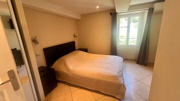A bedroom with a bed, a nightstand, and a window with curtains.