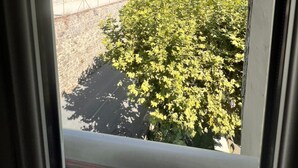 A window view of a building with a stone wall, a tree, and a hill in the background. - Résidence Callas (Callas)