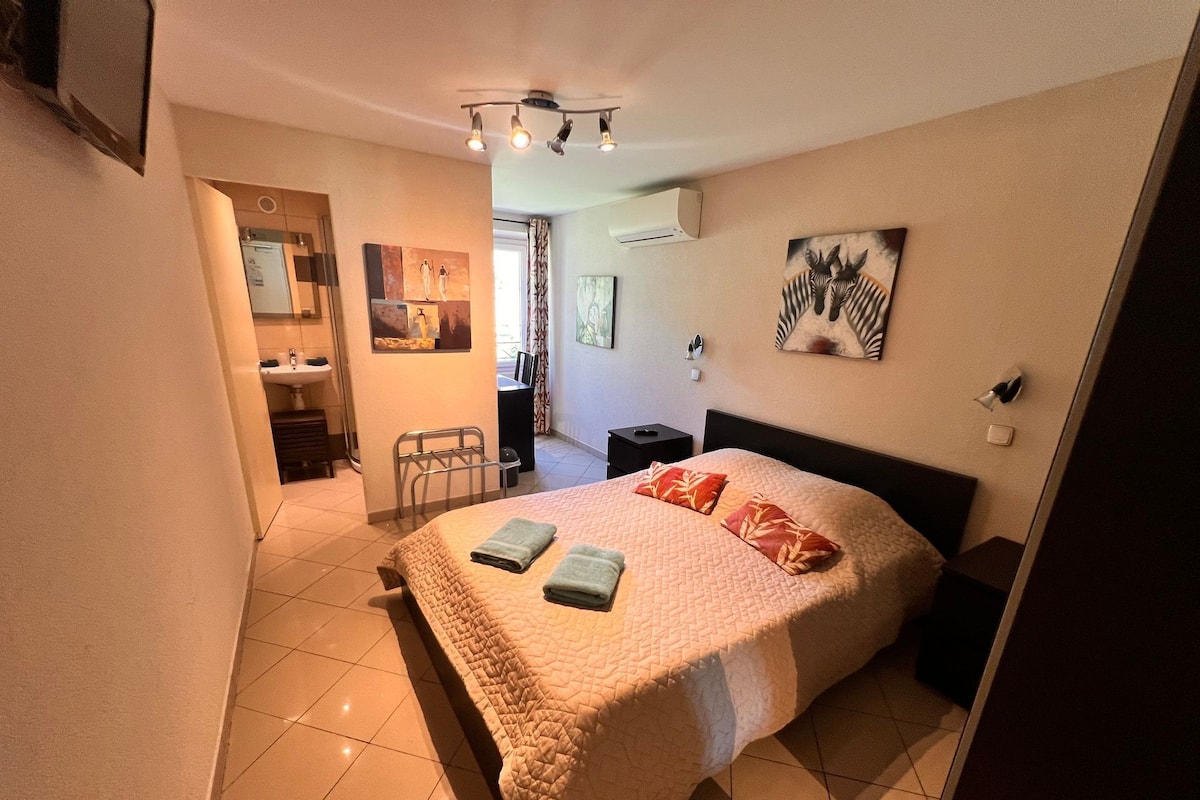 A hotel room with a bed, bedside tables, a mirror, and artwork on the walls.