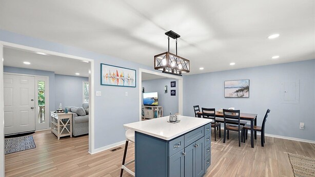 Una cocina moderna con una isla central, comedor con sillas y sala de estar con sofá.