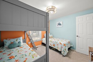 Quarto com duas camas, uma escada, um letreiro de boas-vindas e arte na parede com tema de tartaruga.