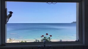 Una ventana con vista al océano y a la playa.