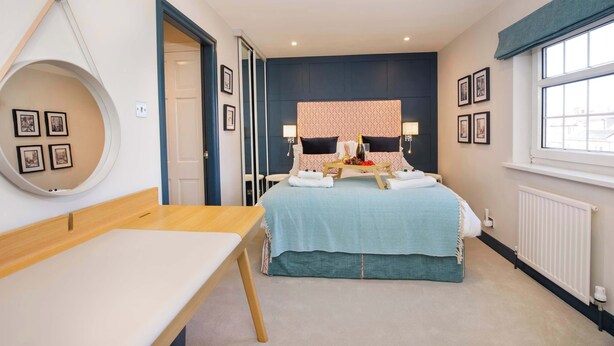 A bedroom with a bed, bedside tables, a round mirror, and framed pictures on the walls.