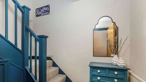 A staircase with blue railings and beige carpeted steps, a blue vanity with drawers, and a sign above the stairs reading "Roundtree's Chocolates."