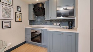 A modern kitchen with grey cabinets, a Bosch oven, a coffee machine, and hexagonal backsplash tiles.