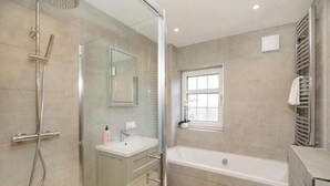 Un bagno moderno con cabina doccia in vetro, una vasca freestanding e un mobile lavabo con specchio.