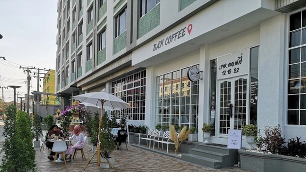 Een coffeeshop met terras, een bord dat aangeeft dat het geopend is, en een menukaart buiten.