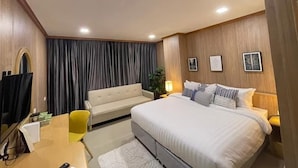 Een moderne hotelkamer met een groot bed, een slaapbank, een bureau en een televisie.
