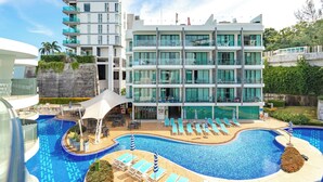 A modern hotel with a swimming pool, multiple balconies, and outdoor seating areas. - Minuets2PatongBeachTwinSandResortSpaC152 (Patong)