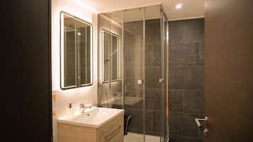 A modern bathroom with a glass-enclosed shower, a vanity with a mirror, and a bathtub.