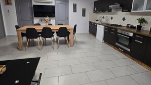 A modern kitchen with a dining area, featuring a wooden table, black chairs, and a black dining table. - Family getaway near the sea (Sainte-Marie-la-Mer)