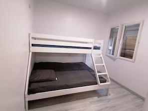 Ein Etagenbett mit einer Leiter, einem Fenster und einer schlichten Wand.