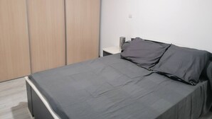 A bedroom with a bed, a nightstand, and a wardrobe. - Family getaway near the sea (Sainte-Marie-la-Mer)