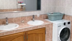 A bathroom with two sinks, a mirror, a washing machine, and a small trash bin. - Family getaway near the sea (Sainte-Marie-la-Mer)