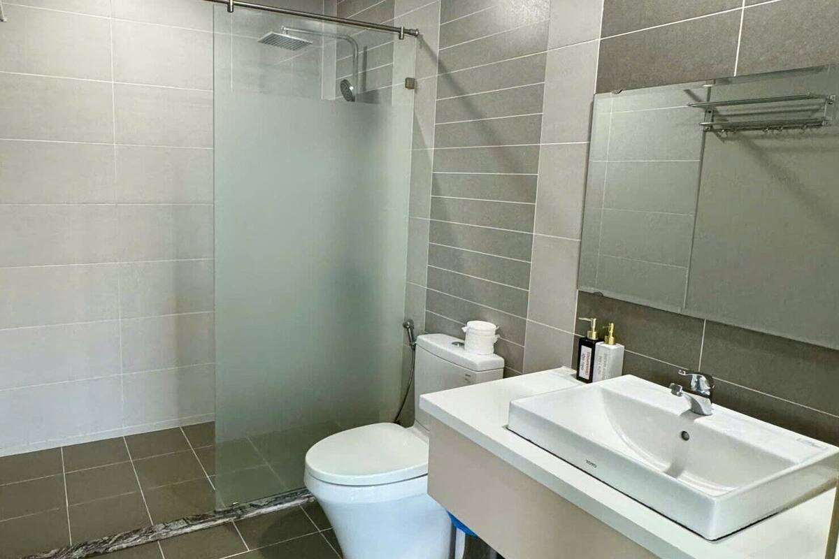 A modern bathroom with a glass-enclosed shower, a white toilet, and a sink with a mirror.