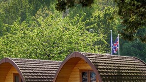 Una hilera de cabañas de madera con techos arqueados y un asta de banderas.