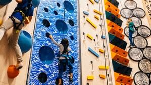 Una pared de escalada con múltiples puntos de agarre y una persona escalando.