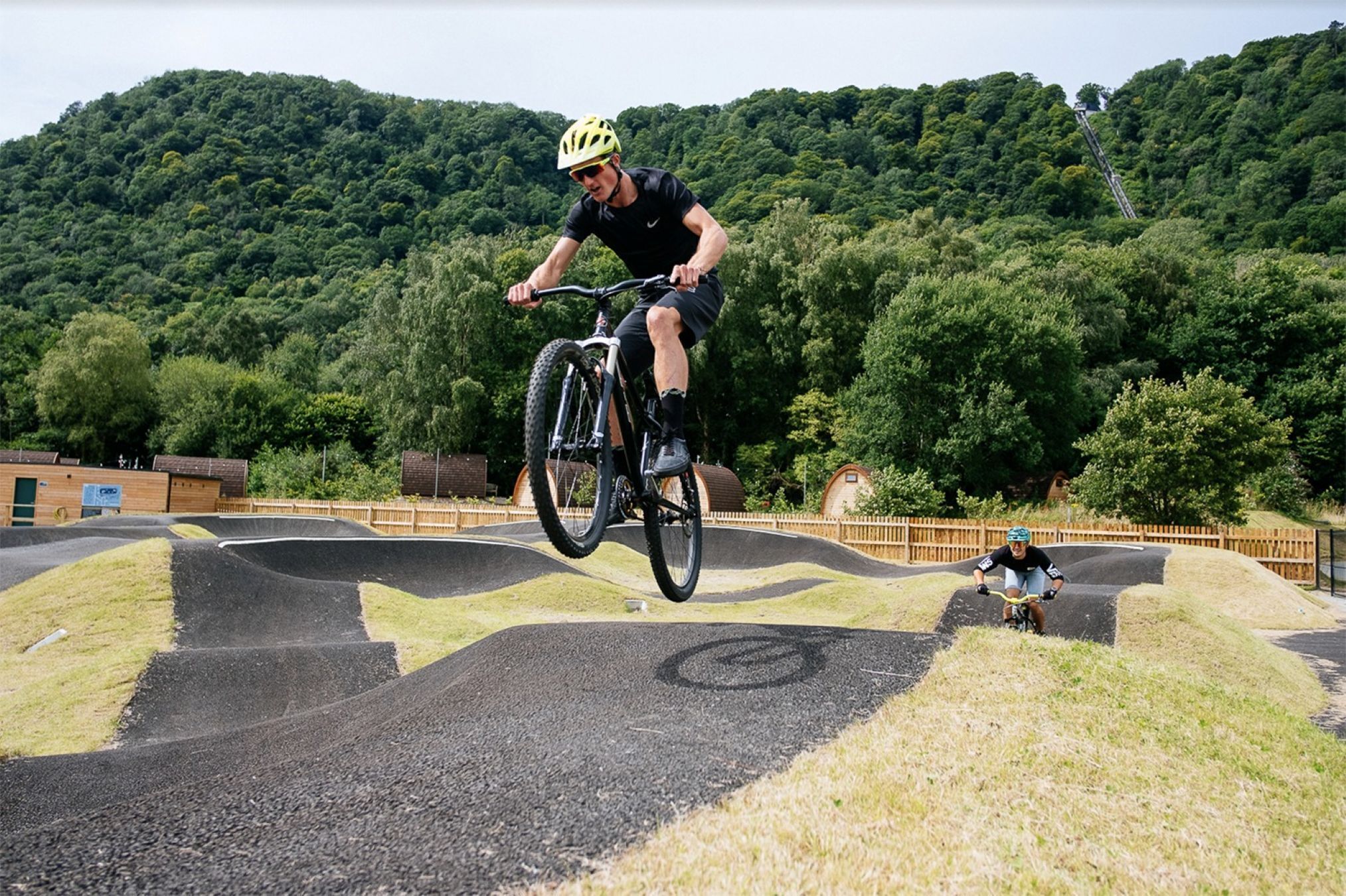 A person riding a bicycle on a track with a natural landscape in the background.