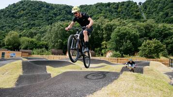 A person riding a bicycle on a track with a natural landscape in the background.