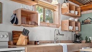 Une cuisine avec des étagères en bois, un évier, une cuisinière et des luminaires suspendus.