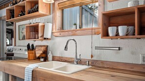 Une cuisine dotée de plans de travail en bois, d’un évier et d’étagères remplies d’ustensiles de cuisine.
