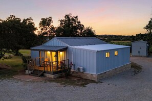 Een klein, laag gebouw met een veranda, een zichtbare open haard en een oprit van grind.