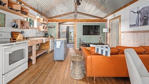 Una cocina amplia con estantes de madera, un comedor y una sala de estar con sofá.