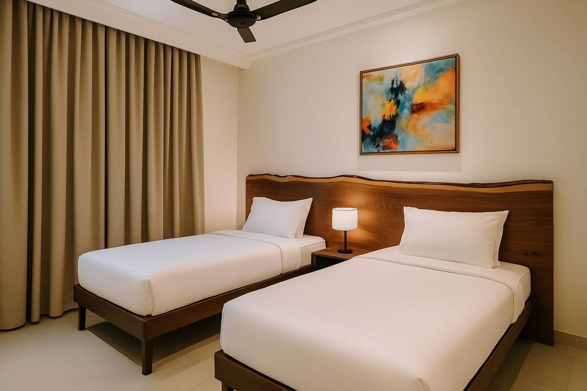 A hotel room with two beds, a ceiling fan, a painting on the wall, and a window with curtains.