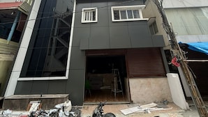 Um edifício de vários andares com design moderno, apresentando uma entrada de garagem e várias janelas.