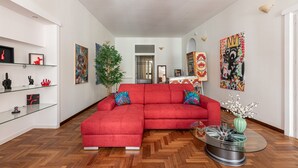 A modern living room with a red sectional sofa, glass shelves, and various artworks. - Giudici Three Bedrooms Apartment by Wonderful Italy (Palermo)